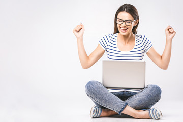 Business concept. Portrait of happy woman in casual sitting on floor in lotus pose and holding laptop isolated over white background.