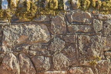 Sandstone wall with moss in sunshine