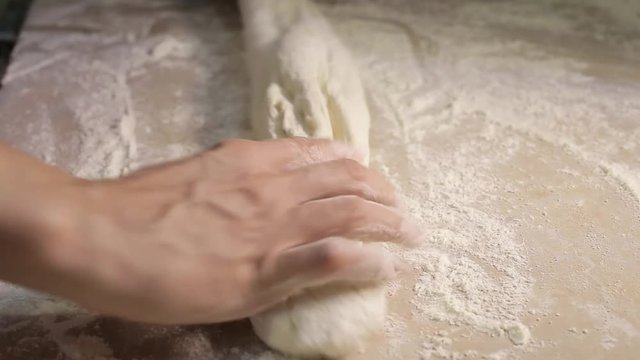 female hands roll out dough on a wooden board, close-up