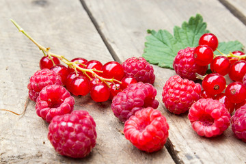 Berries of raspberries and red currants on an old board. Background in a rural style.