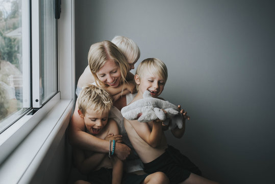 Happy mother with children sitting by window at home
