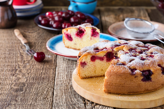 Cherry cake and slice of cake on rustic table