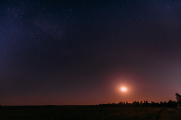 Fototapeta na wymiar Moonrise Above Summer Meadow Landscape In Starry Night