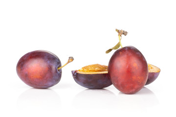 Group of two whole two halves of fresh violet-blue plum vibrant moyer variety isolated on white