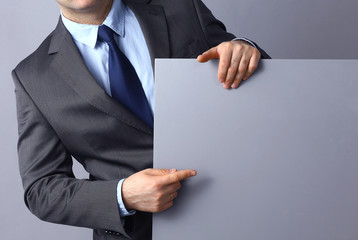 Businessman holding a blank board isolated on grey background