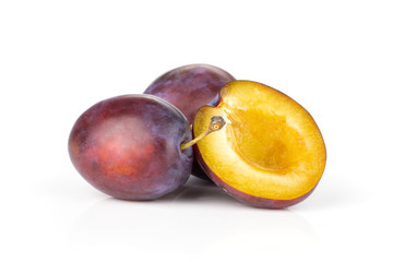 Group of two whole one half of fresh violet-blue plum vibrant moyer variety isolated on white