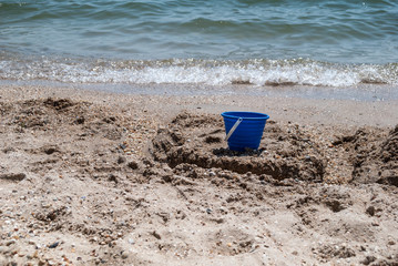 blue bucket on the sand on the beach near the sea