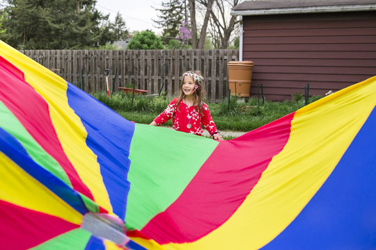 Girl standing by colorful parachute at park