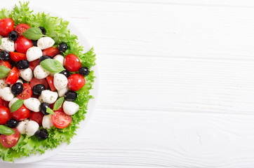 Salad with basil , tomatoes , olives and mozzarella