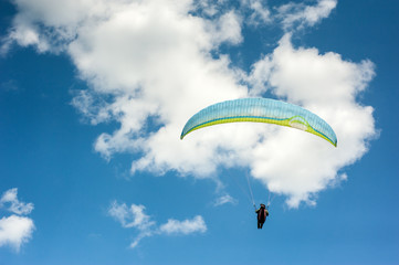 Paraglider flying in the blue sky against the background of clouds. Paragliding in the sky on a sunny day.