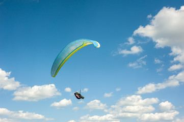 Paraglider flying in the blue sky against the background of clouds. Paragliding in the sky on a...