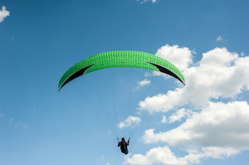 Paraglider flying in the blue sky against the background of clouds. Paragliding in the sky on a...