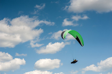Paraglider flying in the blue sky against the background of clouds. Paragliding in the sky on a...
