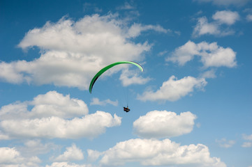 Paraglider flying in the blue sky against the background of clouds. Paragliding in the sky on a sunny day.