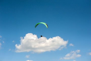 Paraglider flying in the blue sky against the background of clouds. Paragliding in the sky on a...