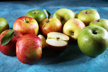 Ripe red apples with leaves on wooden background.
