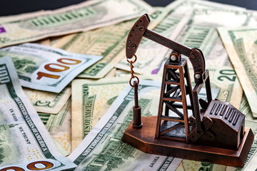 The importance of the petrodollar in the american economy and drilling for oil and profits concept with a oil derrick on top of US dollar bills or notes with copy space