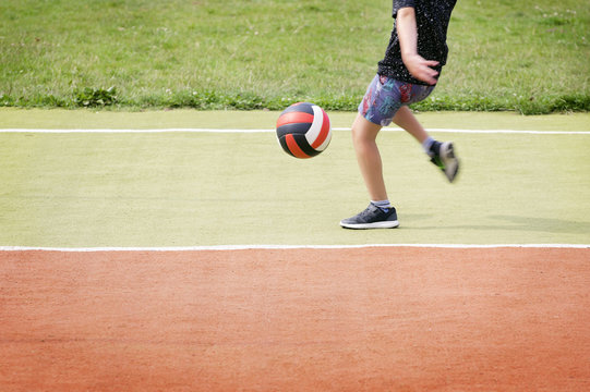 Cropped image of little boy kicking ball on the school sport field.