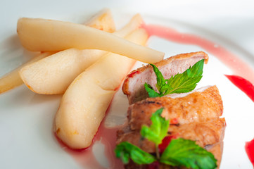Grilled caramelized duck fillet with basil, pieces of pear and cowberry sauce on a plate