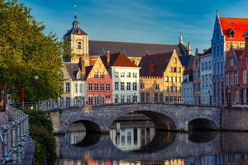 Scenic city view of Bruges canal with beautiful medieval colored houses, bridge and reflections in the evening gold hour, Belgium