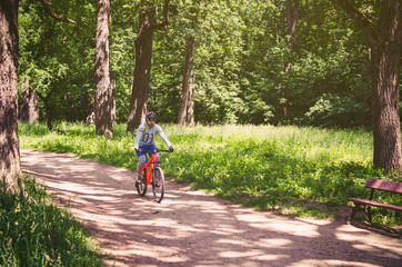 Cyclist in helmet on orange bike riding in park