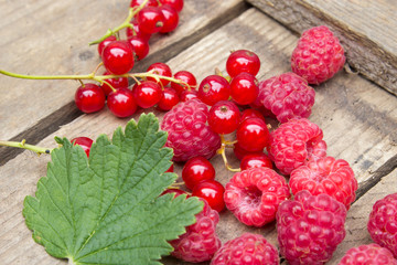 Berries of raspberries and red currants on an old board. Background in a rural style.