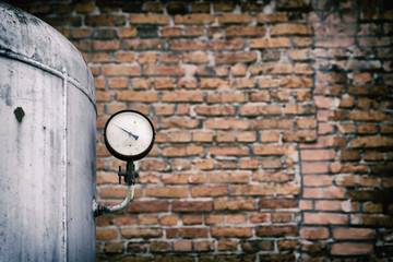 Old pressure gauge of the tank against the backdrop of a brick wall. Pressure sensor