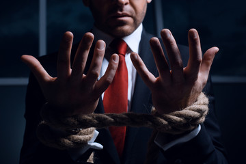 Businessman with hands tied in ropes.