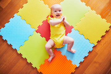 Smiling baby girl lying on play mat