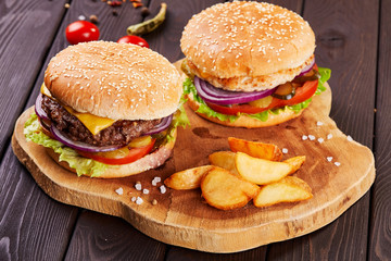 Tasty fresh meat burgers with salad and cheese served on wooden board.