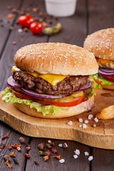 Tasty fresh meat burgers with salad and cheese served on wooden board.