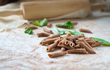 raw whole-grain pasta homemade on the table with flour