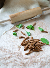 raw whole-grain pasta homemade on the table with flour