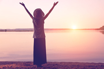 girl in hat meeting sunrise in morning with spreading hands