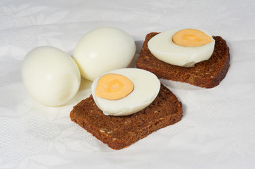 Eggs and two pieces of rye bread on the white napkin