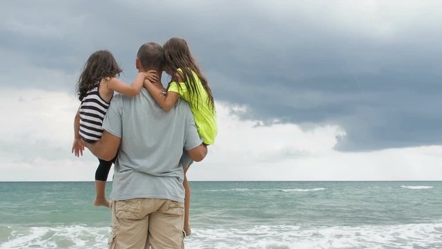 Father with children on the beach. A father with daughters looks at the sea.