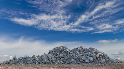 Large granite piles with sky clouds.