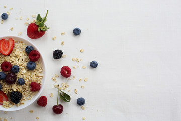 Oatmeal porridge in bowl topped with fresh blueberries, cranberries and homemade crunchy granola