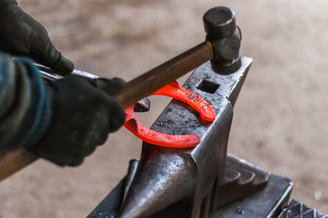 Blacksmith shaping the burning horse shoes