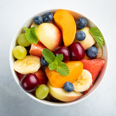 Bowl of healthy fresh fruit salad on a white background. Top view