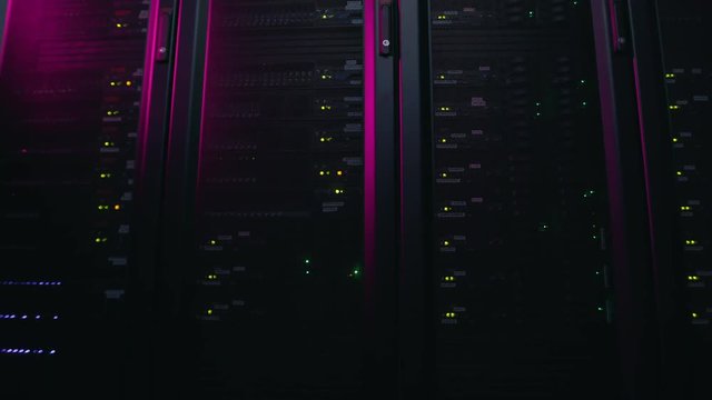 The camera moves to the left parallel to the server racks in the pink light