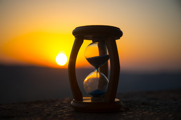 Hourglass Passing of Time Lapse Clouds. An hourglass in front of a bright blue sky with puffy white...