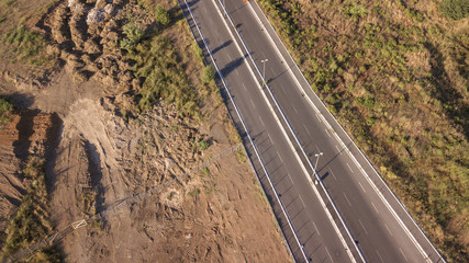 Aerial view of a paved road with a slight curve passing in the middle of a desert land. The roadway has one lane for each direction of travel.