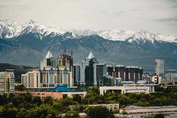 City landscape on a background of snow-capped Tian Shan mountains in Almaty Kazakhstan - obrazy, fototapety, plakaty