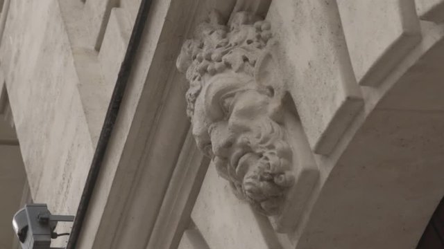 Rotating shot of faun face carved in parisian building