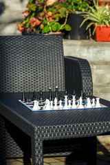 chessboard on the rattan table in the garden in the summer. Travel, vacation, holidays concept  Education concept, chess lesson, training, intellectual game