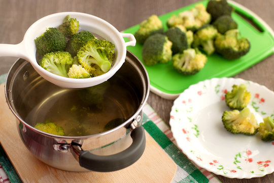 The process of cooking broccoli. Boiled broccoli in a saucepan. Cabbage is filtered in a sieve. Cooking dish of vegetables.