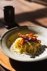 Spaghetti Carbonara with bacon  in ceramic plate with sunshine in the restaurant.