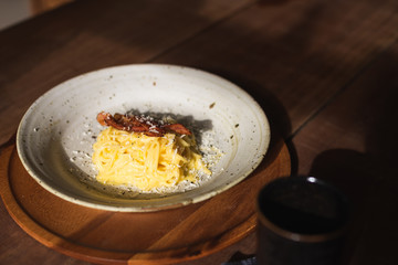 Spaghetti Carbonara with bacon  in ceramic plate with sunshine in the restaurant.