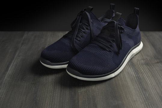 Footwear modern running sport shoes pair on dark wooden and isolated black background. Blue color.